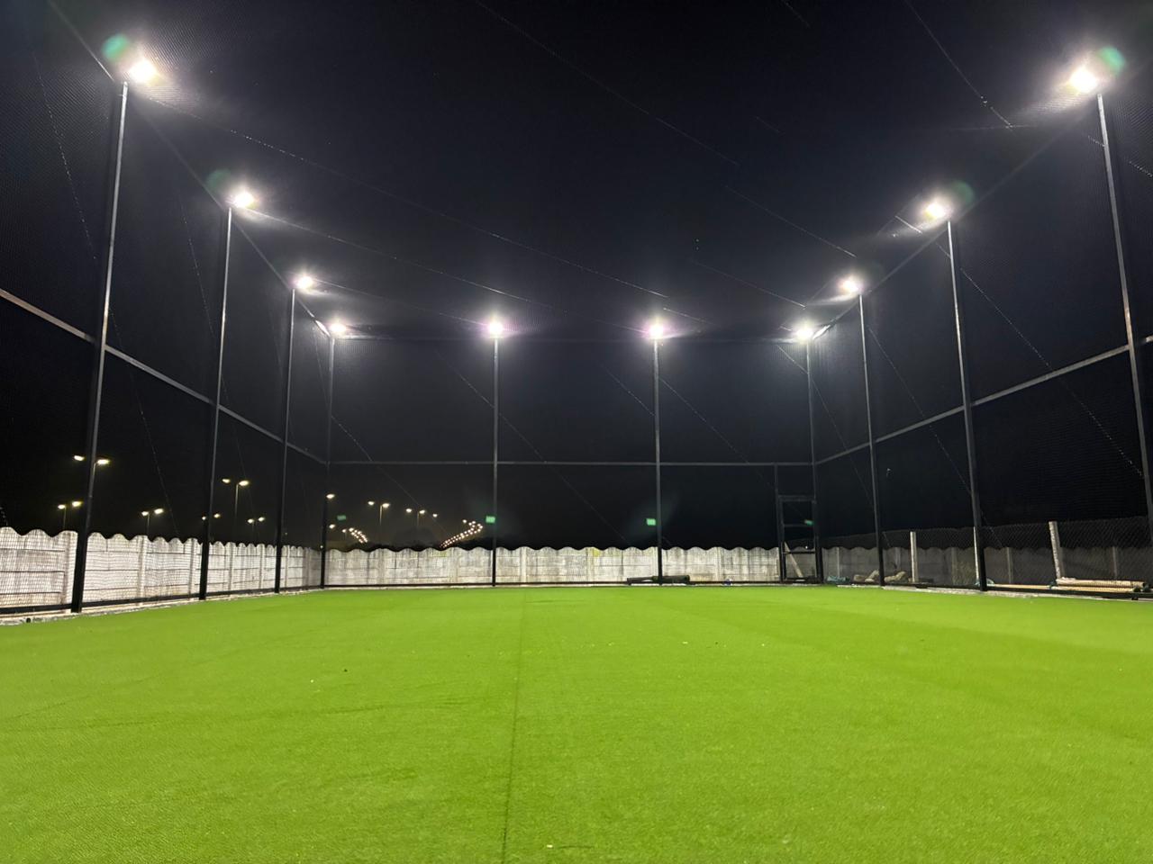 Wide view of the netted pitch under floodlights